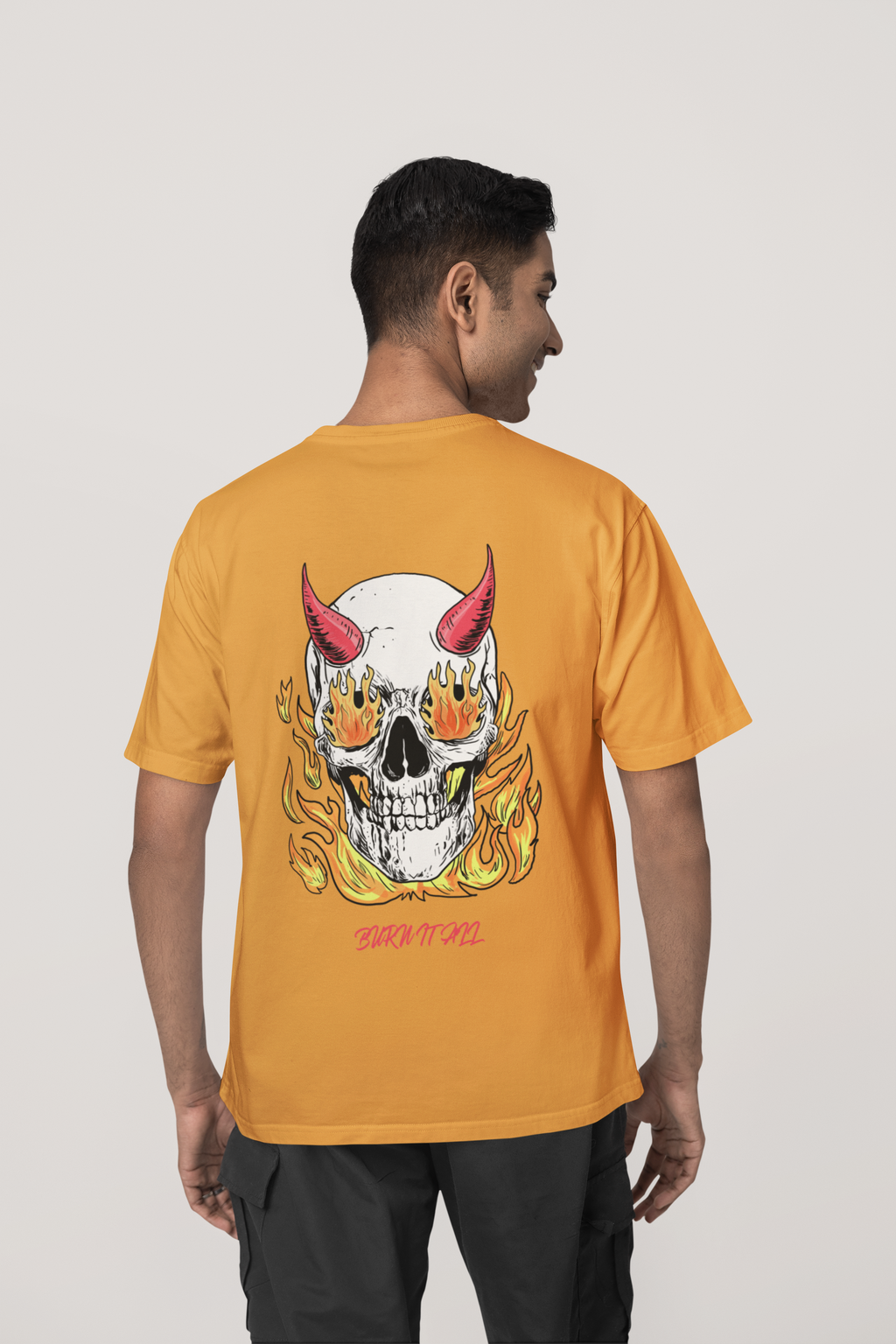 Man wearing Golden yellow 240 GSM oversized t-shirt with large flaming skull and devil horns back print, featuring “Burn It All” text.