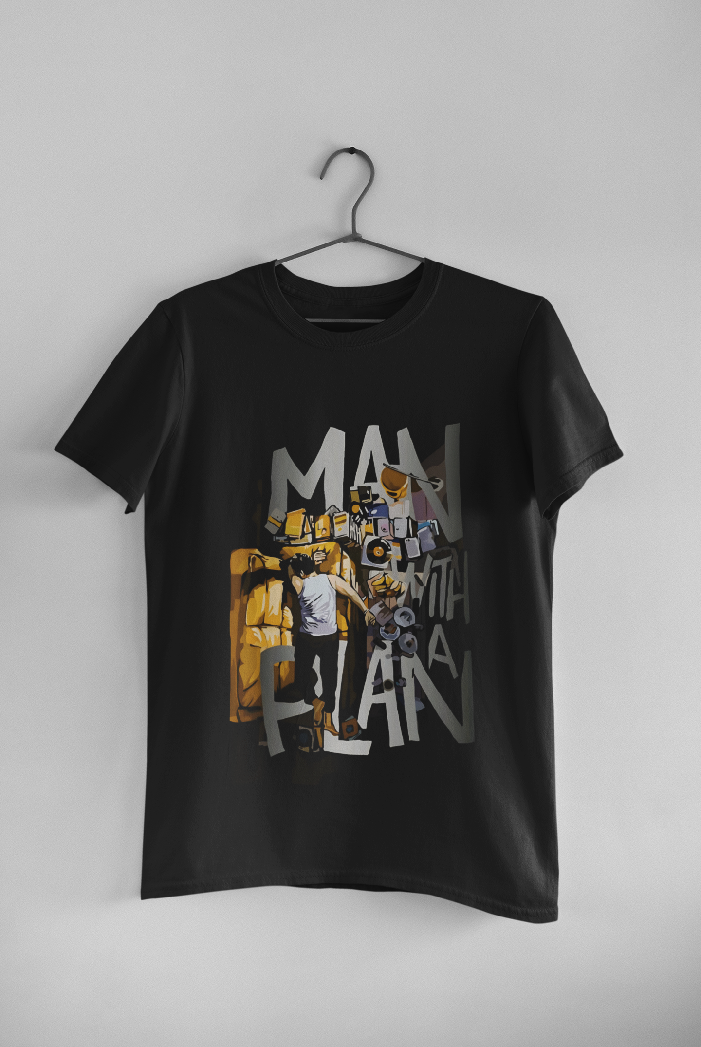 Model wearing black 180 GSM graphic t-shirt with “MAN WITH A PLAN” design, posing in minimal studio with soft lighting.