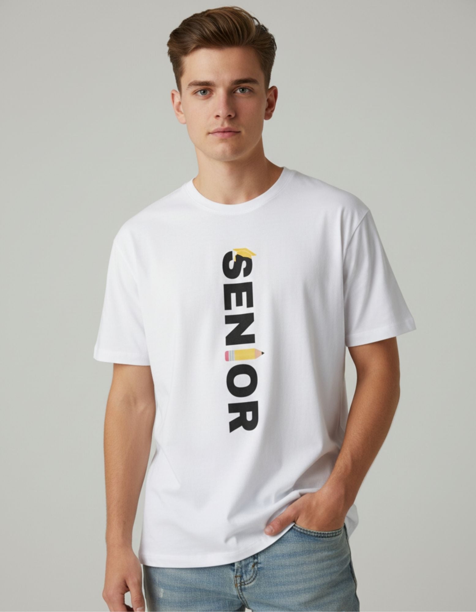 Young man wearing a white cotton T-shirt with "SENIOR" printed vertically in bold black letters, featuring a yellow graduation cap on the "S" and a colorful pencil design on the "I". Styled with light blue jeans for a casual look.
