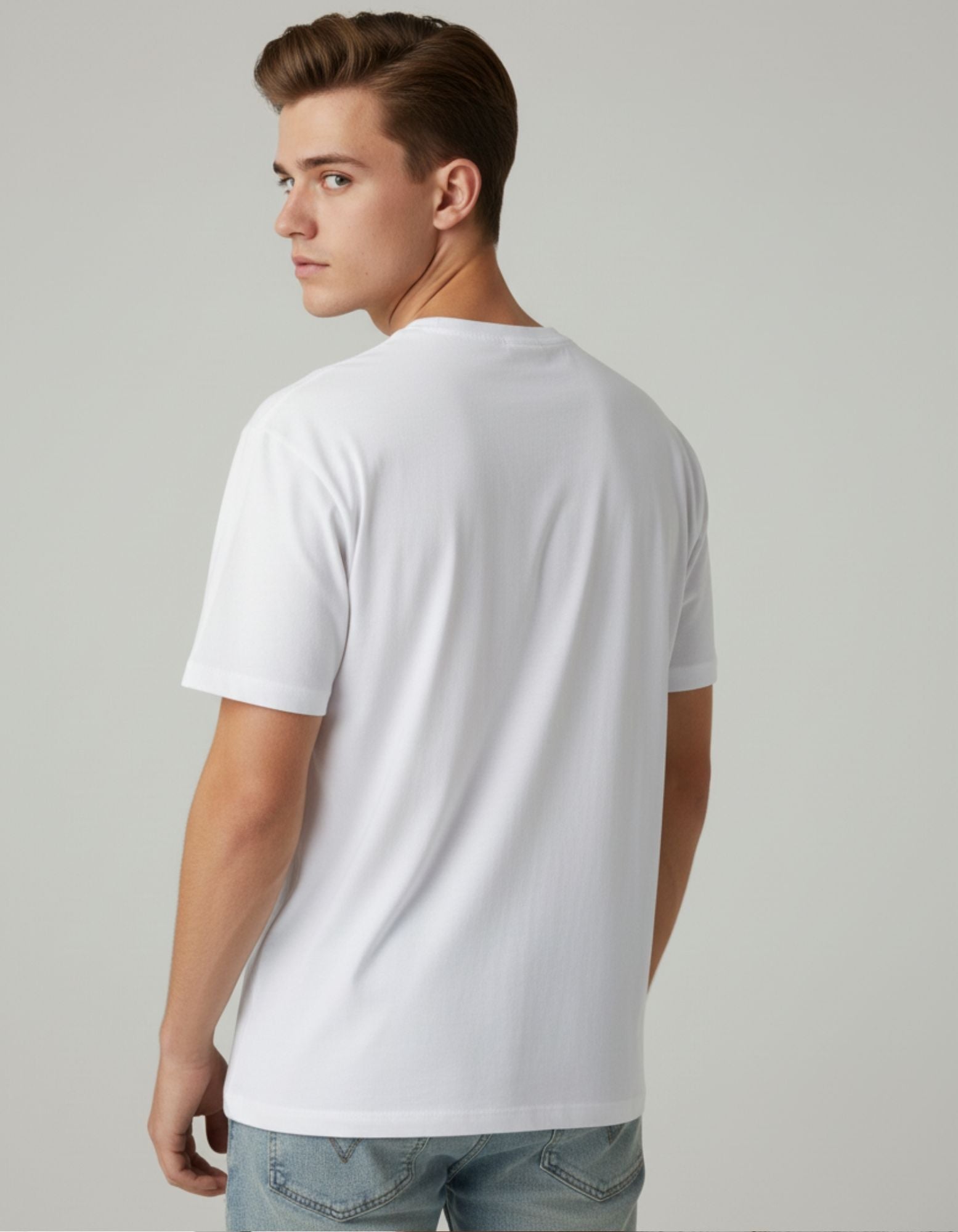 Young man wearing a white cotton T-shirt with "SENIOR" printed vertically in bold black letters, featuring a yellow graduation cap on the "S" and a colorful pencil design on the "I". Styled with light blue jeans for a casual look.