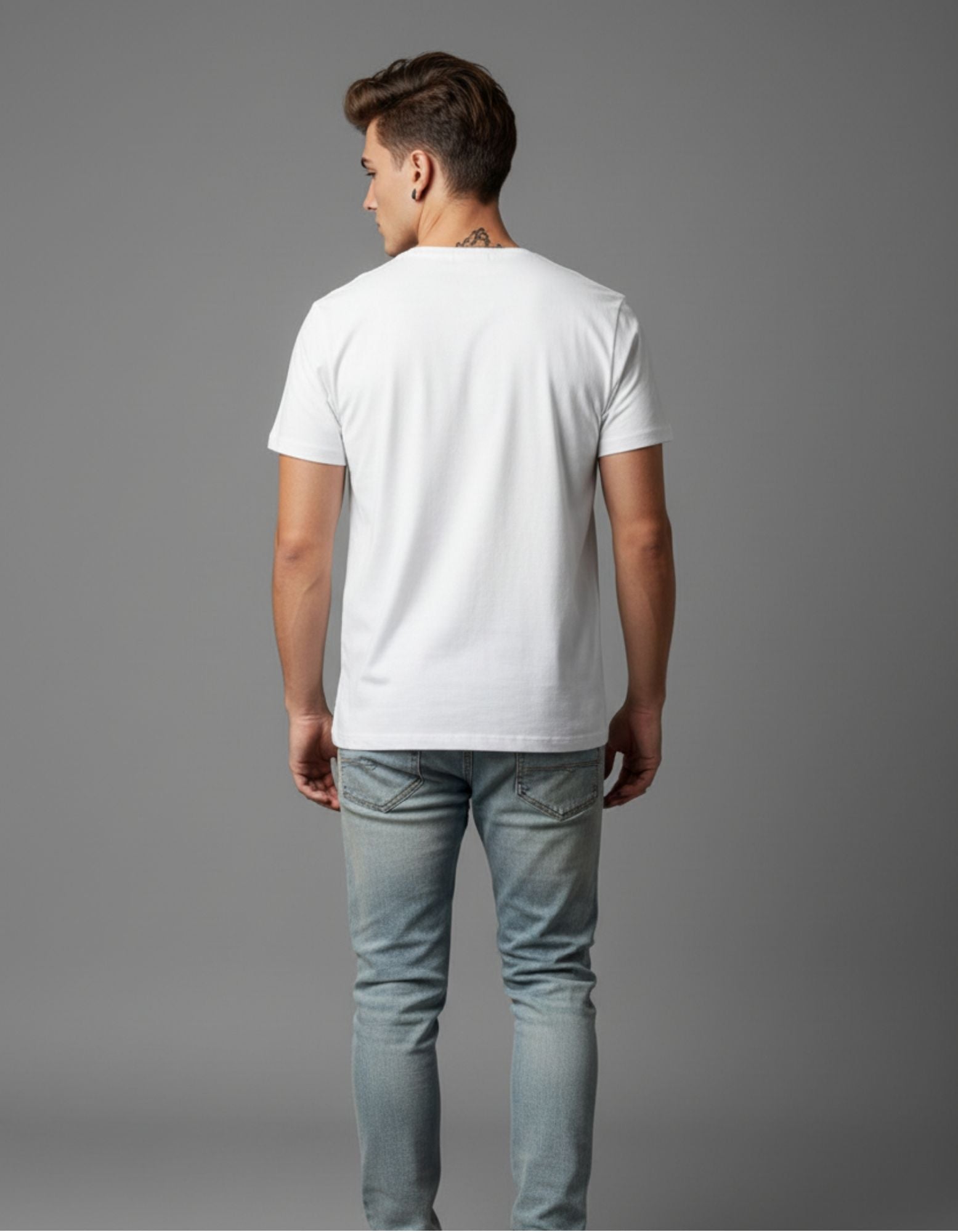 Young man wearing a white graphic T-shirt with a bold quote design that reads “I Live, I Learn” in colorful typography, paired with light blue ripped jeans and red high-top sneakers. Styled in a casual, modern look against a plain grey background.