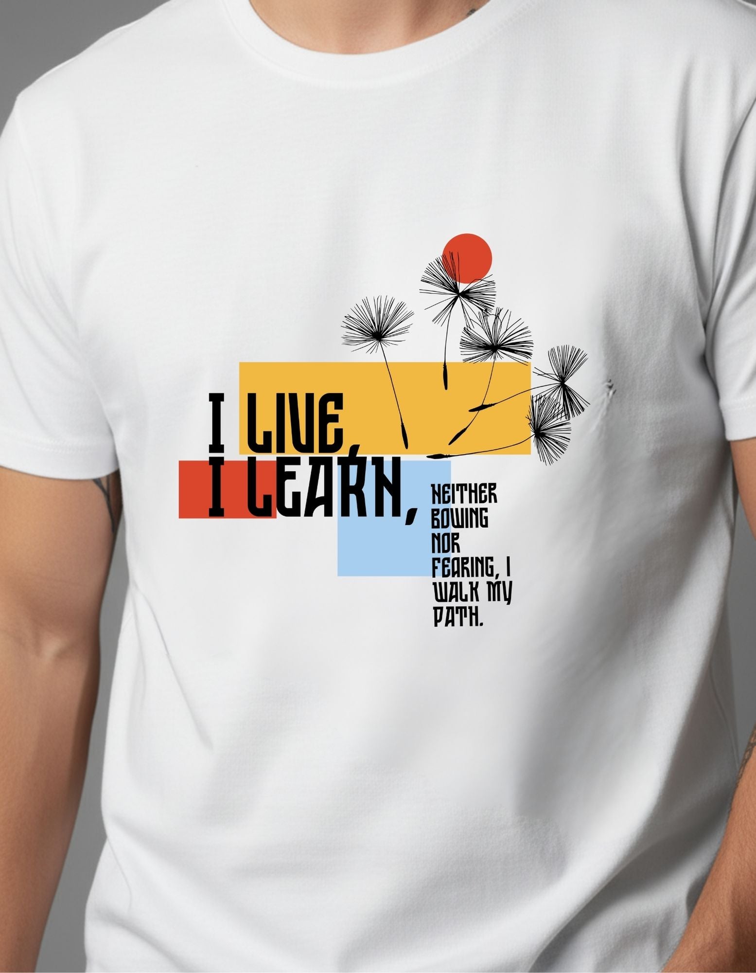 Young man wearing a white graphic T-shirt with a bold quote design that reads “I Live, I Learn” in colorful typography, paired with light blue ripped jeans and red high-top sneakers. Styled in a casual, modern look against a plain grey background.