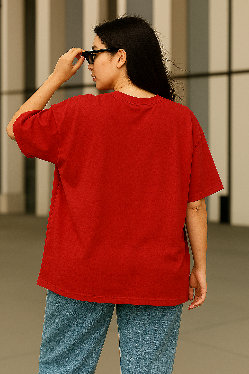 Woman wearing an oversized red graphic t-shirt featuring an anime-style girl with sunglasses and the text "Consciously Chronic Cute", posing confidently with jeans and dark sunglasses.